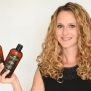 Curly haired blond holding Darshana Natural Shampoo and Conditioner.