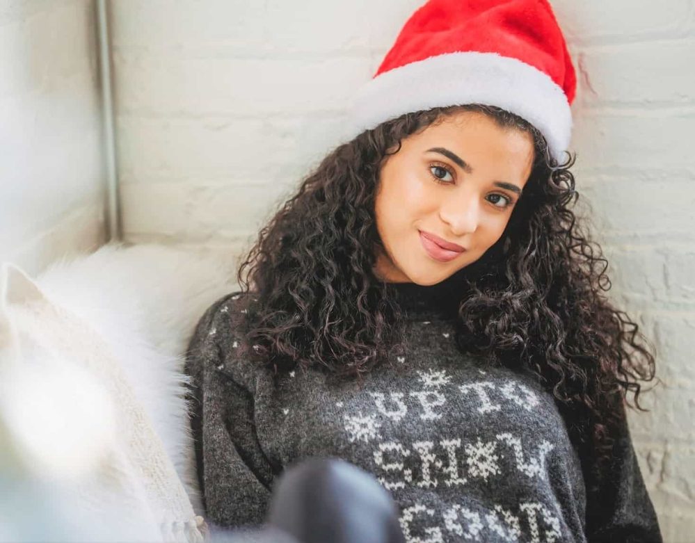 Woman with long curly hair wearing a santa hat
