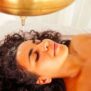 Curly haired woman receiving an ayurvedic oil treatment or oil rinse for her hair.