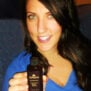 Smiling brunette holding a bottle of Darshana Indian Hair Oil.