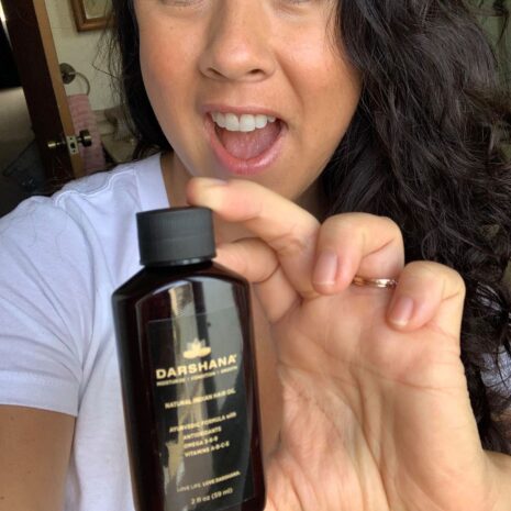 Missy 2 oz. DB Smiling brunette woman holding Darshana Indian hair oil
