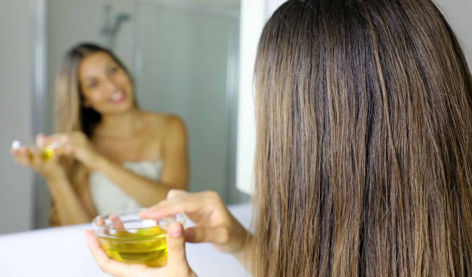 Woman with long brown hair using Ayurveda hair oil