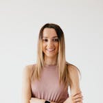 A cheerful young woman standing with arms crossed, exuding confidence and wellness.
